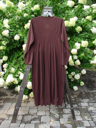 1998 Merino Pria Dress Unpainted Raisin Size 1 displayed on a rack, showcasing its hourglass shape, ribbed round neckline, longer tapering sleeves, and shiny diamond-cut buttons.