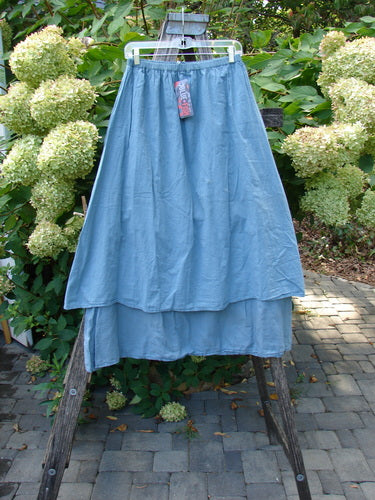 Barclay NWT Batiste Layer Skirt Unpainted Green Sea Size 0 displayed on a wooden stand, showcasing its light-blue layered design and full elastic waist, embodying Bluefishfinder.com's vintage, creative style.