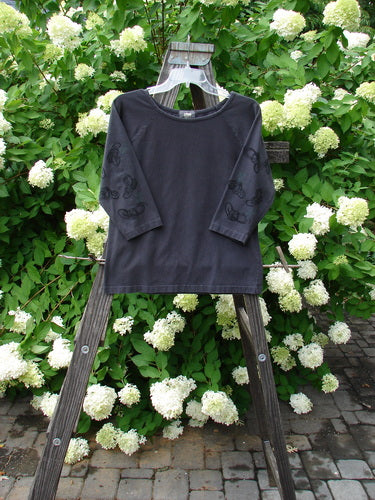 2001 Raglan Tee Top Celtic Knot Licorice Tiny Size 2 displayed on a wooden stand, showcasing long sleeves, shallow rolled neckline, diagonal shoulder seam, and playful paint design.