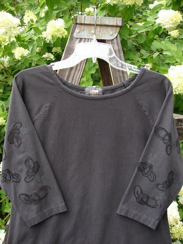2001 Raglan Tee Top Celtic Knot Licorice Tiny Size 2, featuring 3/4 length sleeves, a shallow rolled neckline, playful paint design, and diagonal shoulder seam, displayed on a wooden stand.