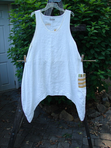 Barclay Linen Single Side Pocket Pinafore Geos White Size 1 hanging outdoors, showcasing its A-line flair, deep scoop neckline, and distinctive side wrap pocket with Geos theme, made of medium weight linen.