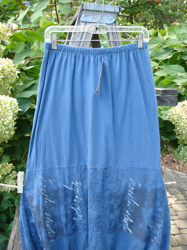 Barclay NWT Sprig Skirt Script Garden Echo Blue Size 0: A lightweight, maxi skirt with a drawstring waist, featuring a paneled lower section with floral-and-script print, hanging amid greenery.