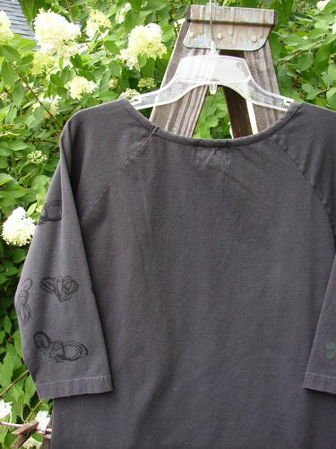 2001 Raglan Tee Top Celtic Knot Licorice Tiny Size 2 displayed on a wooden stand, showcasing 3/4 length sleeves, a shallow rolled neckline, playful paint details, and a fitted feel.