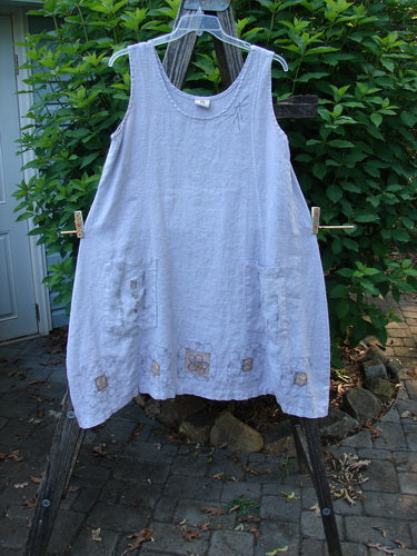 Barclay Linen Pocket Pinafore Mosaic Floral Lavender Size 0 hanging outdoors, showcasing its A-line flair, scoop neckline, and double drop exterior pockets with a mosaic floral design, reflecting Bluefishfinder's unique vintage style.