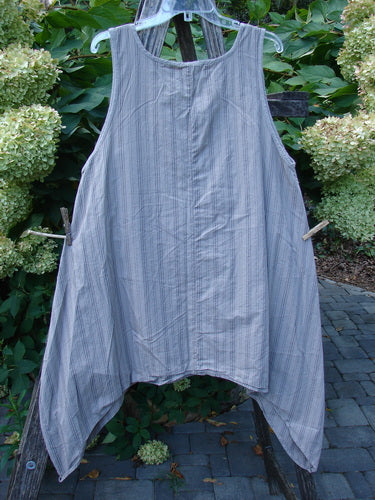 Barclay NWT Percale Hado Shift Stripe Moon Rock Sand Size 1 tunic, sleeveless with an asymmetrical hem and subtle stripes, displayed over a wooden stepladder in a garden setting.