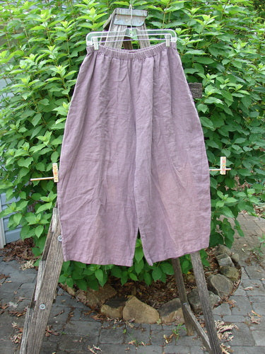 Barclay Linen Every Day Curve Pant Unpainted Dusty Plum Size 1 displayed on a wooden ladder, showcasing its billowing fall, curved sectional panels, thicker elastic waistline, and slight crop length.