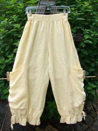 Barclay Linen Tie Bottom Pocket Bloomer Buttercup Size 1 hangs on a clothesline, showcasing the elastic waist, front drop pockets, blooming lower with pull ties, and slightly cropped length.