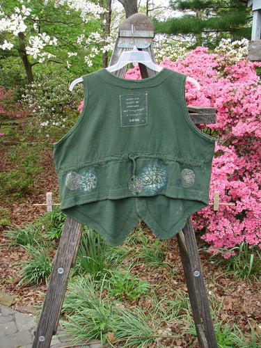 1995 Reprocessed Drawing Room Vest Star Spin Green Tea OSFA displayed on a wooden stand, featuring three ceramic buttons, a shirt-tail hemline, tailored drawcord back, front pocket, and Blue Fish signature patch.