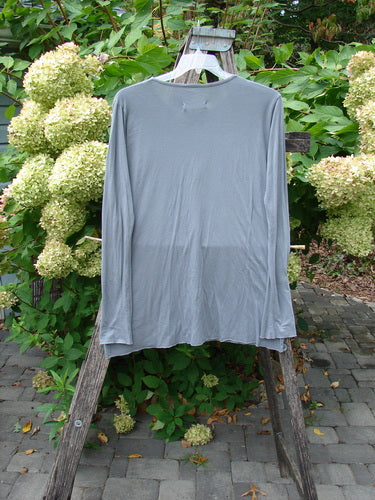 Barclay NWT Batiste Long Sleeved Layering Tee Unpainted Moonlight Size 1 displayed on a wooden ladder in a garden setting, featuring narrowing sleeves, rounded neckline, and raw-edged hem.