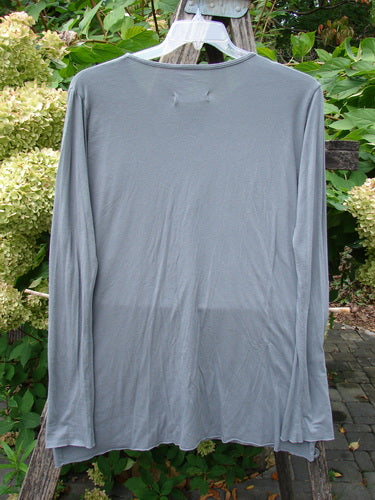 Barclay NWT Batiste Long Sleeved Layering Tee in Moonlight, displayed on a hanger outdoors, showcases long narrowing sleeves, a rounded neckline, and raw cut rolled edgings, ideal for creative layering.