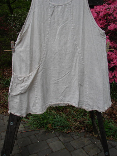 Barclay Slub High Vent Figure 8 Lace Pocket Pinafore Dress Unpainted Crème Size 2 on a clothes rack, showcasing its unique figure-eight seams, wide arm openings, and lacy hem accents.