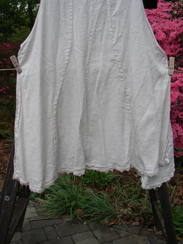 Barclay Slub High Vent Figure 8 Lace Pocket Pinafore Dress Unpainted Crème Size 2 hanging on a clothesline, showcasing its unique figure-eight seams, lacy hem accents, and exterior pockets.