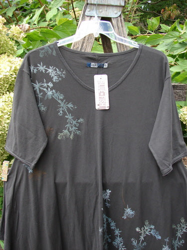 Barclay NWT Origami Tunic Top Floral Branch Black Sand Size 0 displayed on a clear hanger against a wooden ladder, showcasing its loose fit, subtle floral-vine print, and unique hemline design.