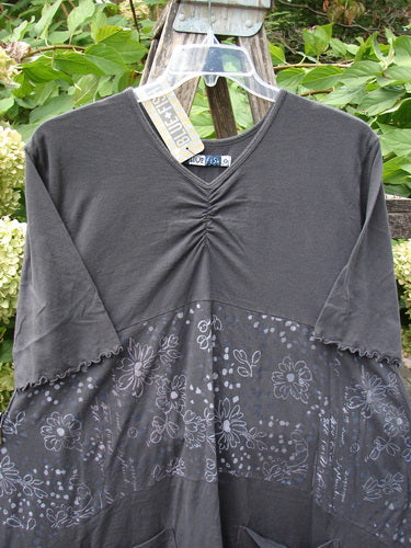 Barclay NWT Perfect Day Pocket Tunic Dress Script Daisy Black Sand Size 0 features a charcoal gray upper with V-neck and ruching, floral-patterned lower half, displayed on a hanger against a natural backdrop.