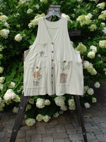 1994 Fishing Vest Magic Garden Aloe OSFA: A white vest with a design on it, featuring a deep V-shaped neckline, three front painted pockets, and an oversized rear painted pocket. Made from medium weight cotton jersey, this vest is part of the Spring Collection of 1994.