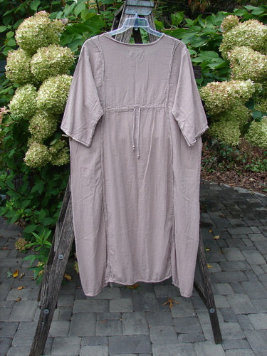 The Barclay NWT Textured Batiste Linen Haystack Dress Unpainted Oriel Size 0, showcased on a wooden stepladder, features elbow-length sleeves, a drawstring waist, and a lightweight, crinkled fabric.