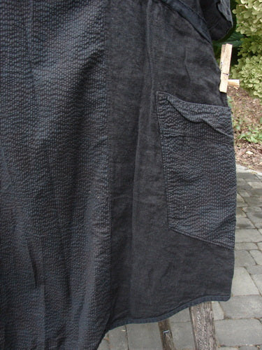 Barclay NWT Linen Pucker Heart and Soul Pocket Dress Unpainted Black Size 0 features a textured fabric with a rectangular patch pocket, displayed on a wooden support, highlighting its unique stitch detailing.