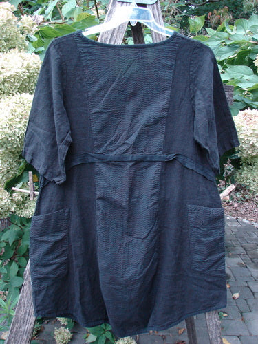 Barclay NWT Linen Pucker Heart and Soul Pocket Dress Unpainted Black Size 0, featuring a scoop neckline, textured fabric, patch pockets, and a seam across the chest, draped on a wooden trellis.