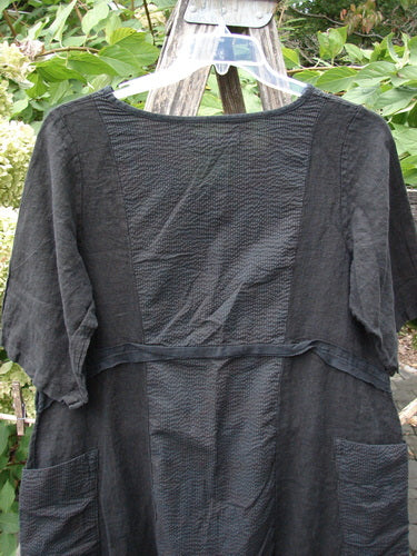 Barclay NWT Linen Pucker Heart and Soul Pocket Dress Unpainted Black Size 0 displayed outdoors, features a textured A-line shape, scoop neckline, elbow-length sleeves, horizontal waist band, and contrasting patch pockets.