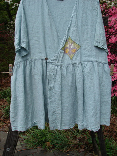 1999 Linen Adjustable Wrap Dress Butterfly Water OSFA displayed on a clothesline, featuring a cross-over front, gathered waist, flouncy skirt, and butterfly print.