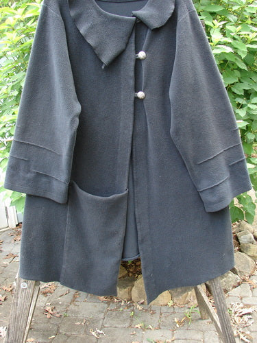 Barclay Celtic Moss Asymmetrical Collar Coat Unpainted Black Size 0 featuring a unique offset collar, three-button closure, dramatic hemline, and bell sleeves, elegantly displayed on a rack.