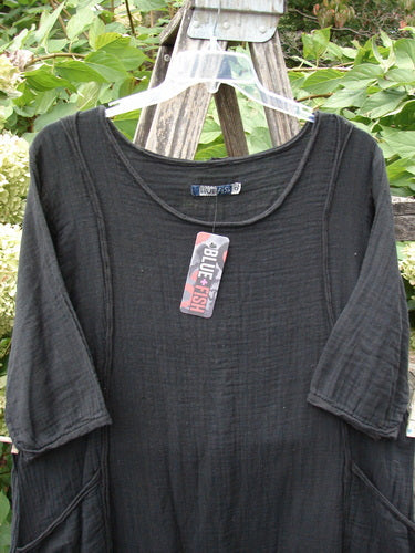 Barclay NWT Gauze Daily Pocket Dress Unpainted Jet Black Size 0, featuring three-quarter sleeves and an A-line shape, displayed on a ladder against a garden backdrop, showcasing Blue Fish's vintage-inspired creativity.