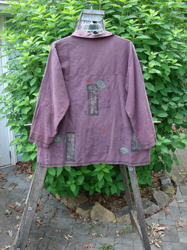Barclay Hemp Cotton Metal Button Workshirt Asian Script Plum Wine Size 0 displayed on a wooden rack, highlighting its metal button front, shirttail hemline, and distinctive Asian script detailing.