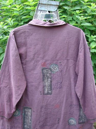 Barclay Hemp Cotton Metal Button Workshirt with Asian Script in Plum Wine, featuring metal buttons, contrasting stitchery, and a shirttail hemline, showcased close-up on a hanger.