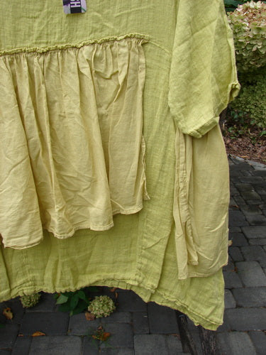 Barclay NWT Gauze Batiste Petal Urchin Flounce Dress Unpainted Citron Size 1, featuring a loose fit with a peplum-style waist and short sleeves, displayed outdoors with a natural backdrop.