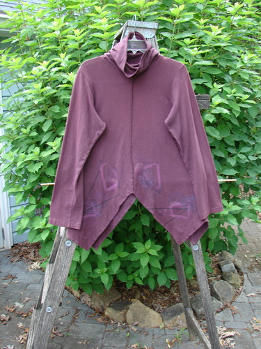 Barclay Cotton Lycra Symmetrical Turtleneck Top with a unique galaxy theme, featuring a mock turtleneck, varying hemlines, vertical stitch detailing, and long sleeves, displayed on a wooden stand.