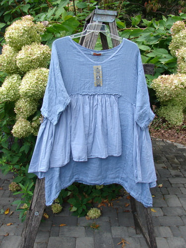 Barclay NWT Gauze Batiste Petal Urchin Flounce Dress Unpainted Dusty Sky Size 1 features a loose fit, gathered waist, asymmetrical hem, and three-quarter sleeves, elegantly displayed on a wooden stepladder outdoors.
