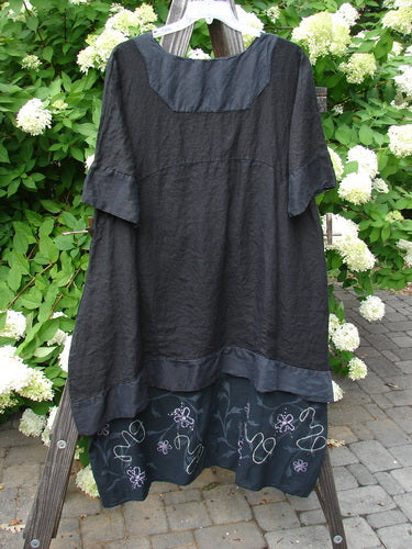 Barclay Linen Crossover Two Tier Dress Floral Black Size 2 displayed on a rack, featuring a crossover V neckline, wide cuffed sleeves, double-layered flow, and double side seam pockets.