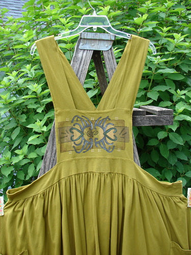 Barclay Overall Jumper Celtic Sun Glazed Tile OSFA displayed on a wooden easel, showcasing crisscross back straps, oversized side pockets, and a wide, full gathered skirt, embodying vintage charm.