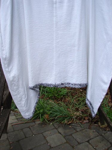 Barclay Crinkle Gauze Contrast Ditsy Daisy Pinafore Unpainted White Size 2 displayed on a wooden frame, highlighting the scoop neckline, deeper arm openings, and full hem with floral accents.