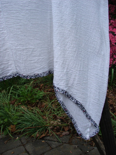 Barclay Crinkle Gauze Contrast Ditsy Daisy Pinafore Unpainted White Size 2 hanging on a clothesline, showcasing its sweet varying hem, scoop neckline, and full hem with floral print accents.