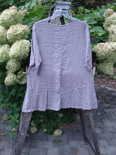 Barclay NWT Linen Simple Tunic Top Wing Mountain Opal Mauve Size 1, displayed on a clear hanger against a rustic ladder, highlighting its flowy A-line shape and three-quarter sleeves.
