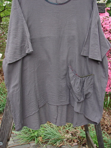Barclay Gauze Contrast Ditsy Daisy Pocket Top Unpainted Stone Size 2 displayed on a hanger, showcasing its wide neckline with a floral pattern, exterior pocket, and drawcord back.