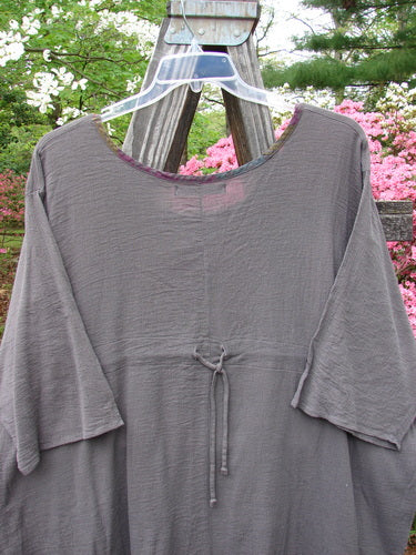 Barclay Gauze Contrast Ditsy Daisy Pocket Top in unpainted stone, displayed on a hanger, featuring a deeper neckline, widening hem, exterior drop pocket, and drawcord back.