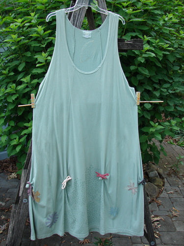 Barclay Constellation Jumper Garden Folly Aloe Size 1, displayed outdoors, features a scooped neckline, dimensional hemline with pointed accents, sectional vertical panels, and a garden-themed design.