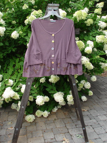 Barclay Peplum Pocket Jacket Magic Garden Dusty Plum Size 2 displayed on a wooden stand, featuring ceramic buttons, peplum hem, and three-quarter sleeves with painted floral design.