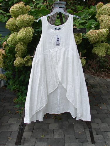 Barclay NWT Linen Tulip Midlayer Overpiece Unpainted White Size 0 displayed on a ladder, featuring an asymmetrical, draped front hem, rounded neckline, and sweeping A-line flare, with sales tag visible.