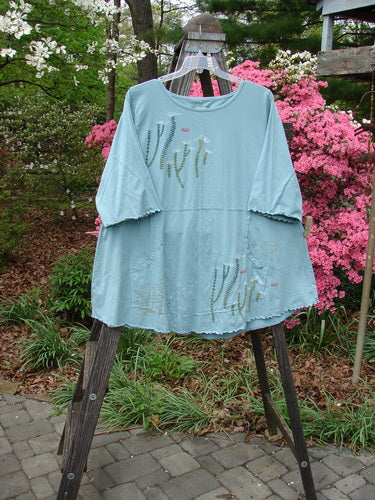 Barclay Three Quarter Sleeved Cafe Pocket Top Fern Blue Tourmaline Size 2 displayed on a stand with a longer A-line tunic shape and double side entry kangaroo pocket.