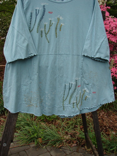 Barclay Three Quarter Sleeved Cafe Pocket Top Fern Blue Tourmaline Size 2 features a floral pattern, three-quarter sleeves, a tunic shape, feminine neckline, kangaroo pocket, and curly edgings, perfect for summer.