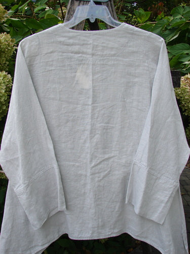 Barclay NWT Linen Basque Cardigan Unpainted Dove Size 0 displayed on a hanger, featuring a deep V-neck, dippy sides, vented hemline, wide cuffable sleeves, and oversized shell buttons.