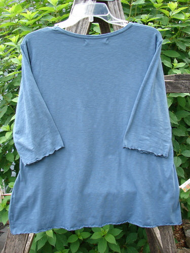 Barclay Slub Three Quarter Sleeved Cafe Tee Unpainted Tealen Size 1, displayed on a clothes rack, showcases its three-quarter sleeves, rounded neckline, and distinctive curly edging, embodying BlueFishFinder's vintage and creative style.