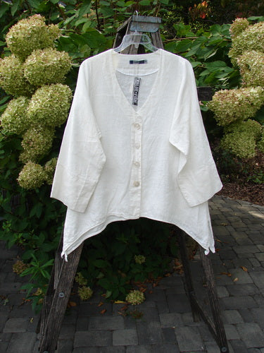 Barclay NWT Linen Basque Cardigan Unpainted White Size 0 displayed on a wooden stand, featuring a deep V-neck, oversized shell buttons, and wide cuffable sleeves, as part of a vintage-inspired summer collection.