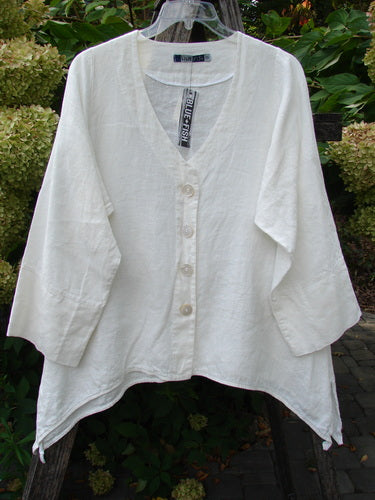 Barclay NWT Linen Basque Cardigan Unpainted White Size 0, featuring a deep V-neck, asymmetrical hem, and oversized shell buttons, hanging on a clear hanger with garden backdrop.