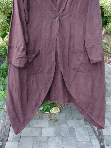 Barclay NWT Linen Geoides Pocket Duster in Armagnac Red Plum, draped over a wooden bench, features a single-button closure, large patch pockets, and an asymmetrical hem in textured linen blend fabric.