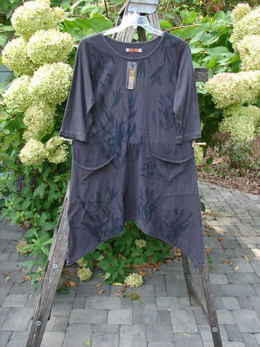 Barclay NWT Sunny Day Pocket Tunic Dress Flutter Bamboo Steel Meteorite Size 1 displayed on a wooden stepladder, featuring elbow-length sleeves, asymmetrical hem, and subtle botanical prints, with retailer's tag attached.