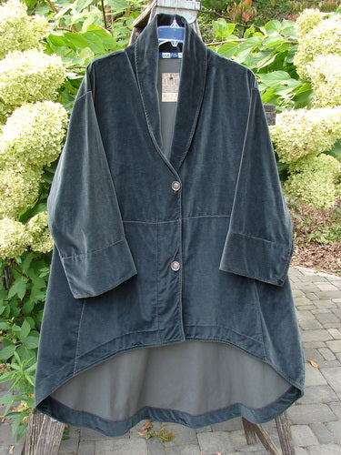 Barclay NWT Velvet Opera Pocket Coat in Unpainted Blue Black, features a shawl-style collar, two front buttons, and a high-low hem, displayed against hydrangea bushes on a plastic hanger.